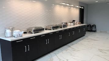 A modern kitchen with a marble countertop, black cabinets, and overhead lighting.
