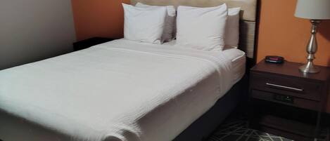 Una cama bien tendida con sábanas blancas en una habitación de hotel.