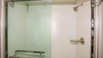 A glass-enclosed shower with a handheld showerhead and a towel rack.