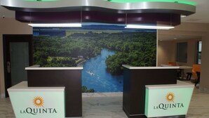 Ett receptionsområde med två diskar, var och en märkt med "La Quinta", och en stor väggmålning som föreställer en flod och en skog bakom diskarna.