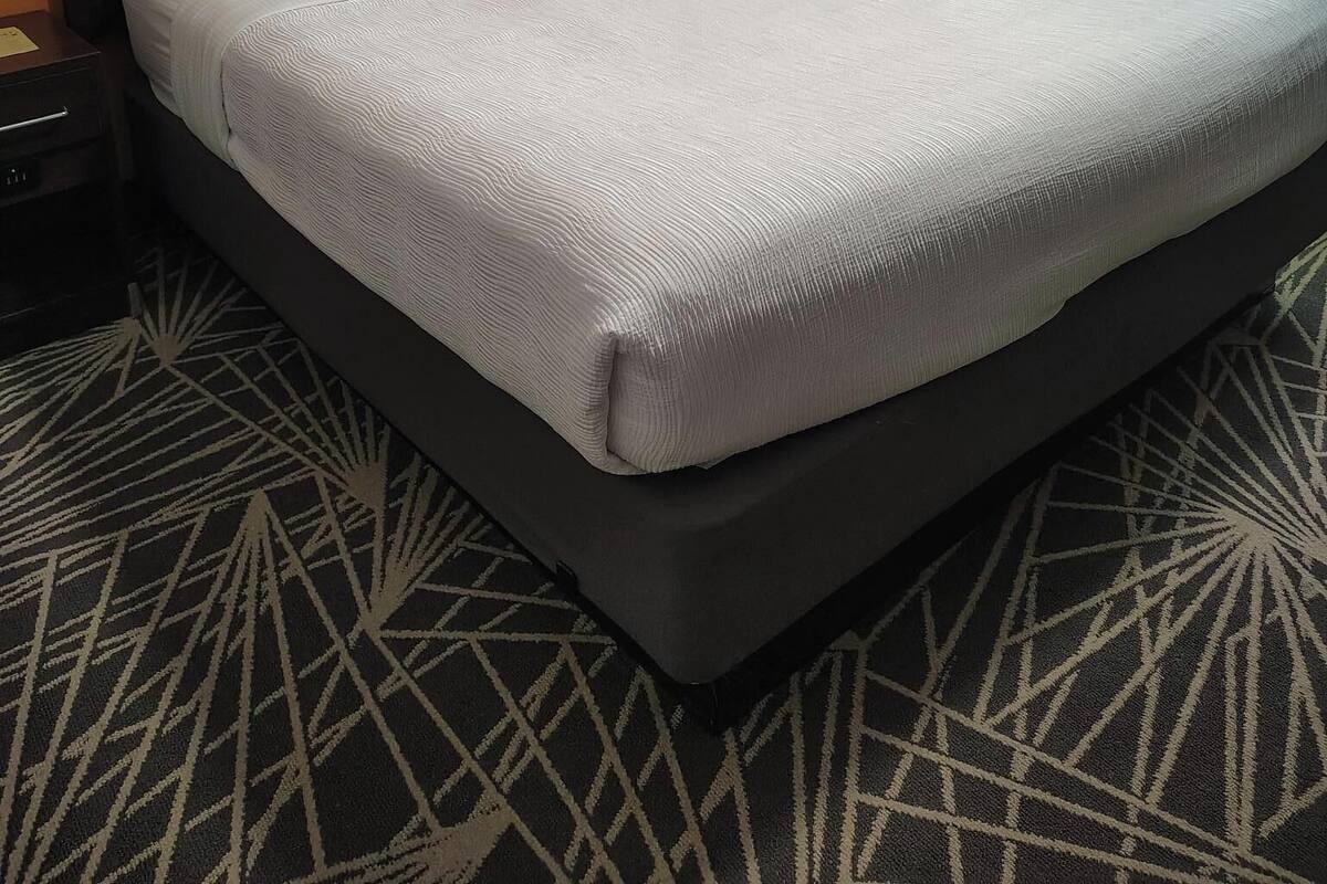 A hotel room with a large bed, a nightstand, a lamp, and a window with curtains.