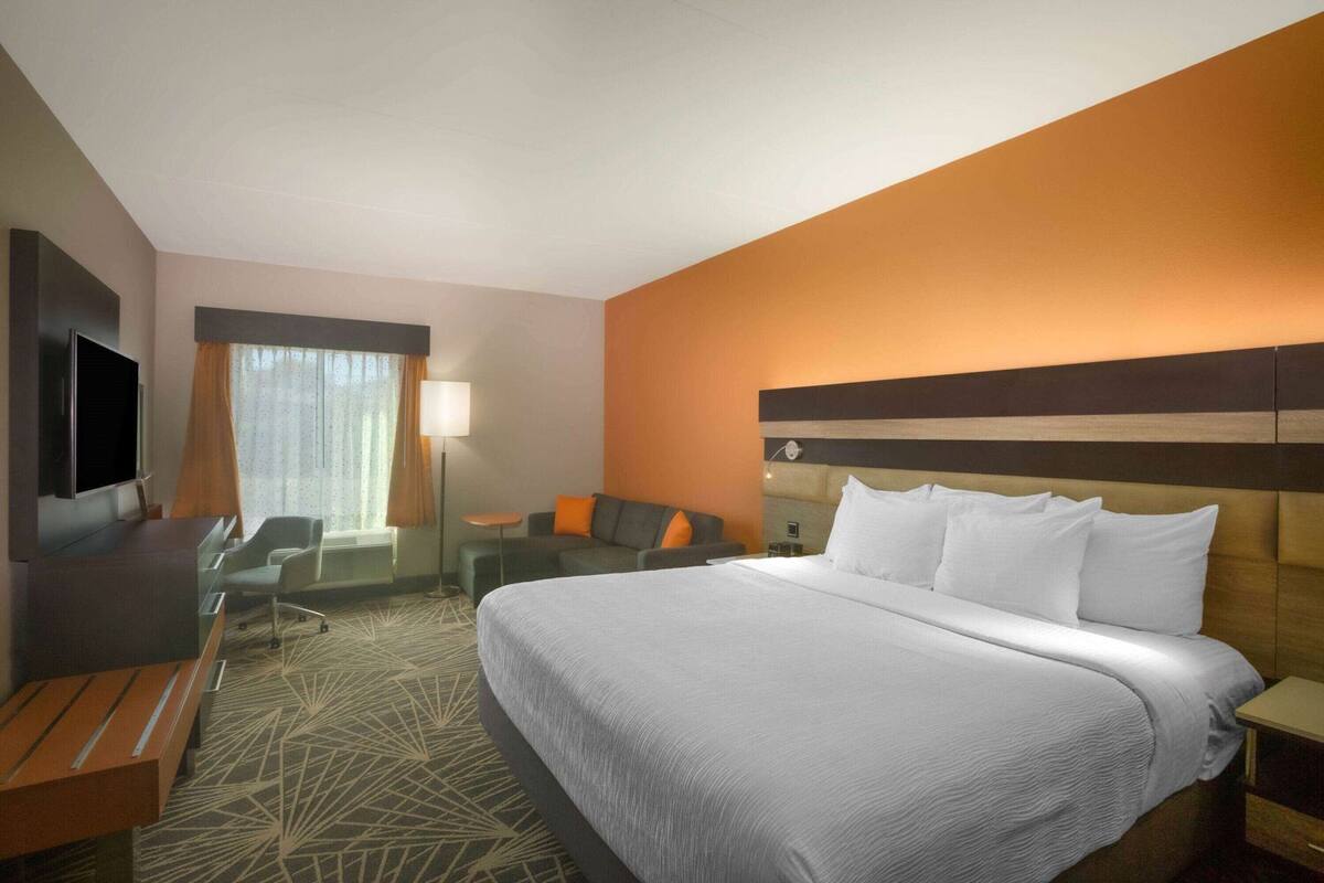 A hotel room with a large bed, a desk, a TV, and a seating area.
