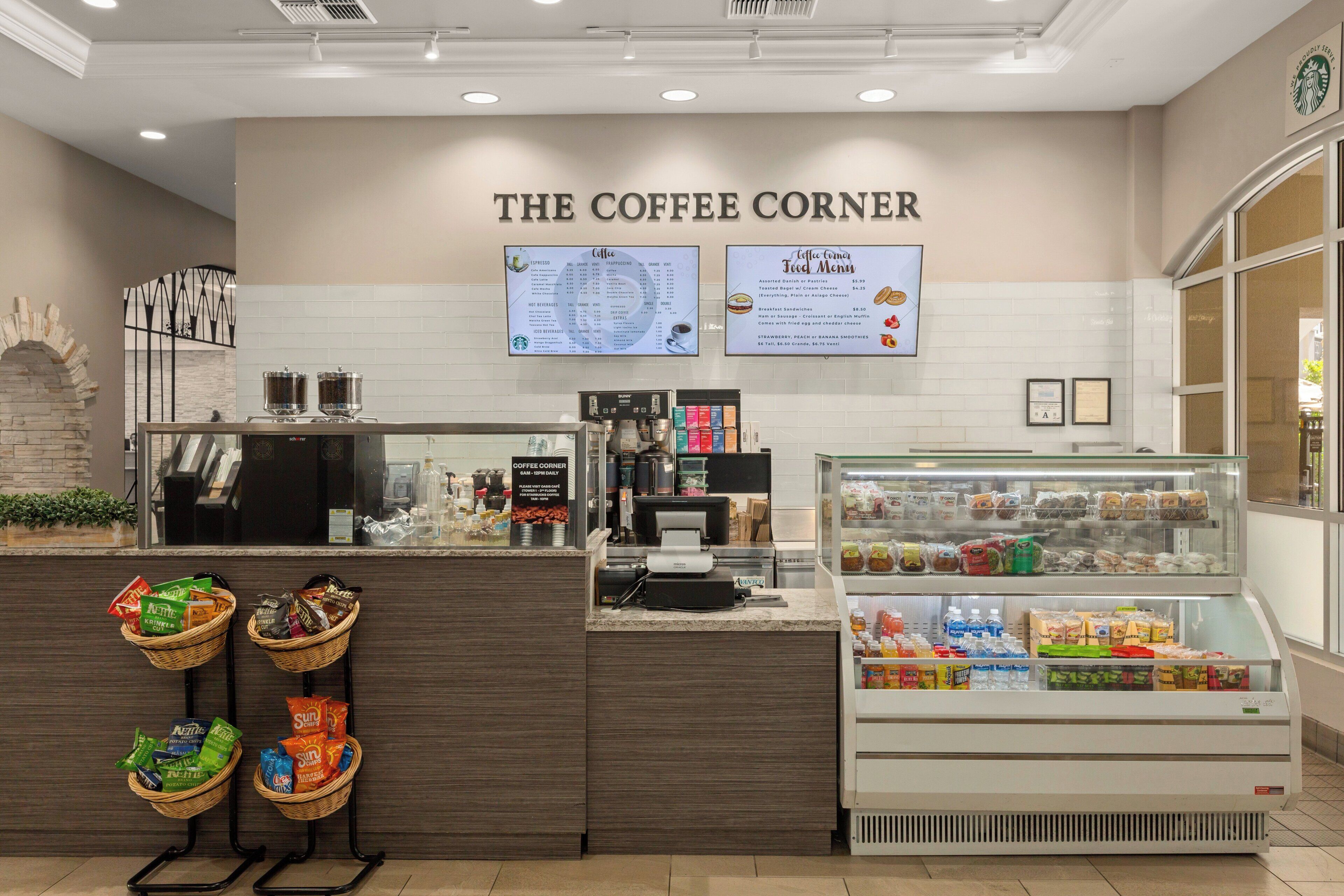 A coffee shop counter with a menu board, a cash register, and a display case with snacks.
