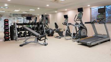 A gym with treadmills, dumbbells, and weight machines.