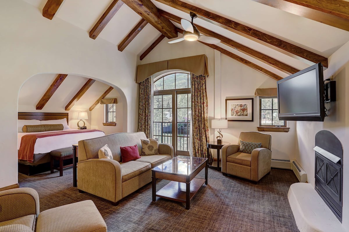 A cozy room with a bed, two sofas, a coffee table, and a fireplace.
