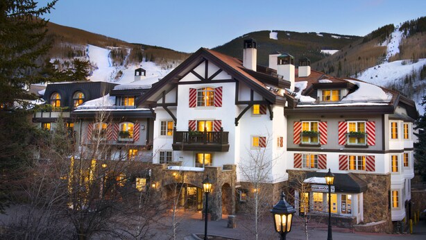 Un hotel grande de varios pisos con un estilo arquitectónico tradicional, que cuenta con balcones con barandillas y ventanas con persianas.
