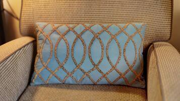 A close-up of a chair with a textured fabric and a decorative pillow with a geometric pattern.