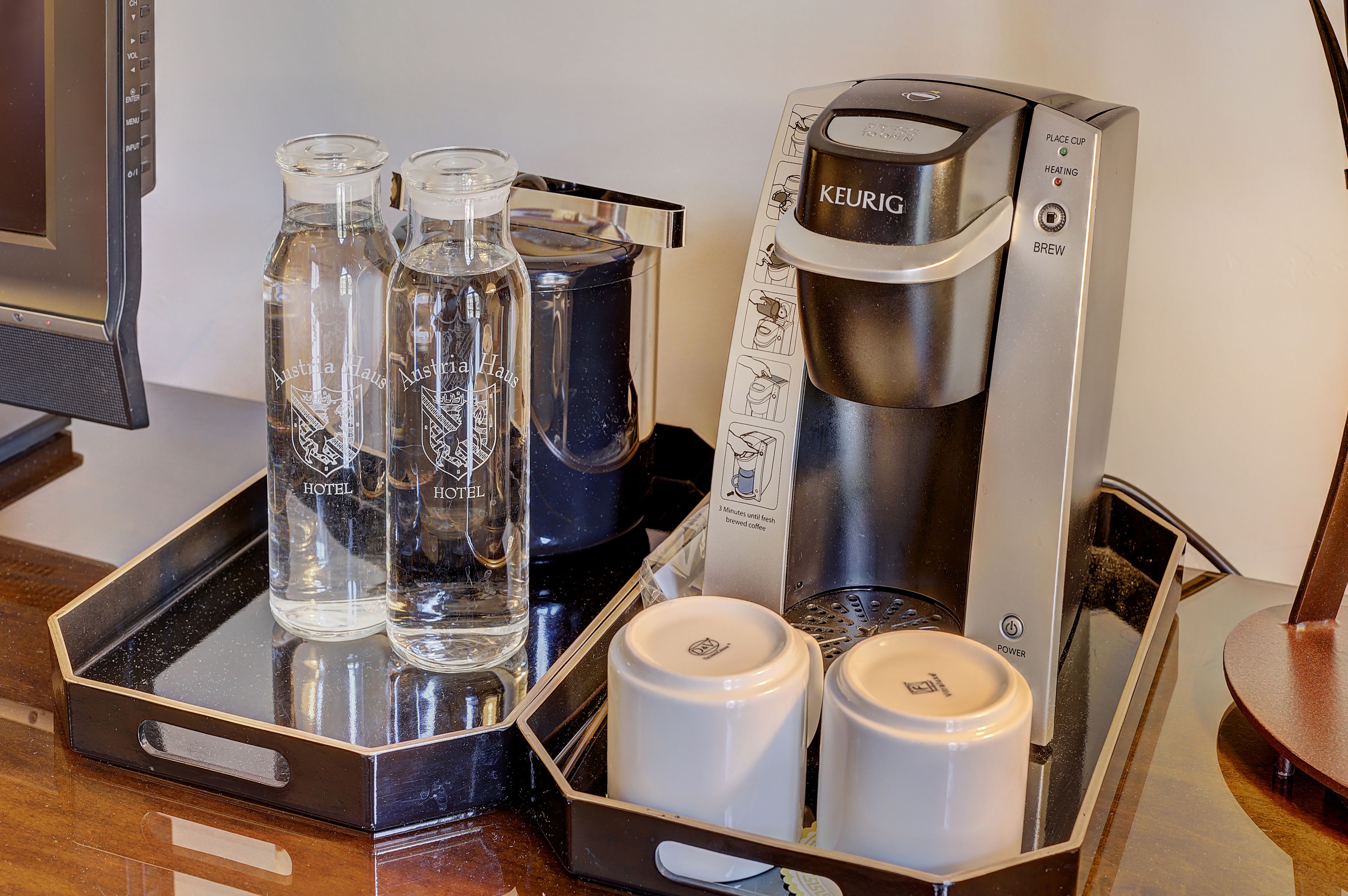 Una cafetera, dos botellas de agua y dos tazas blancas sobre una bandeja.