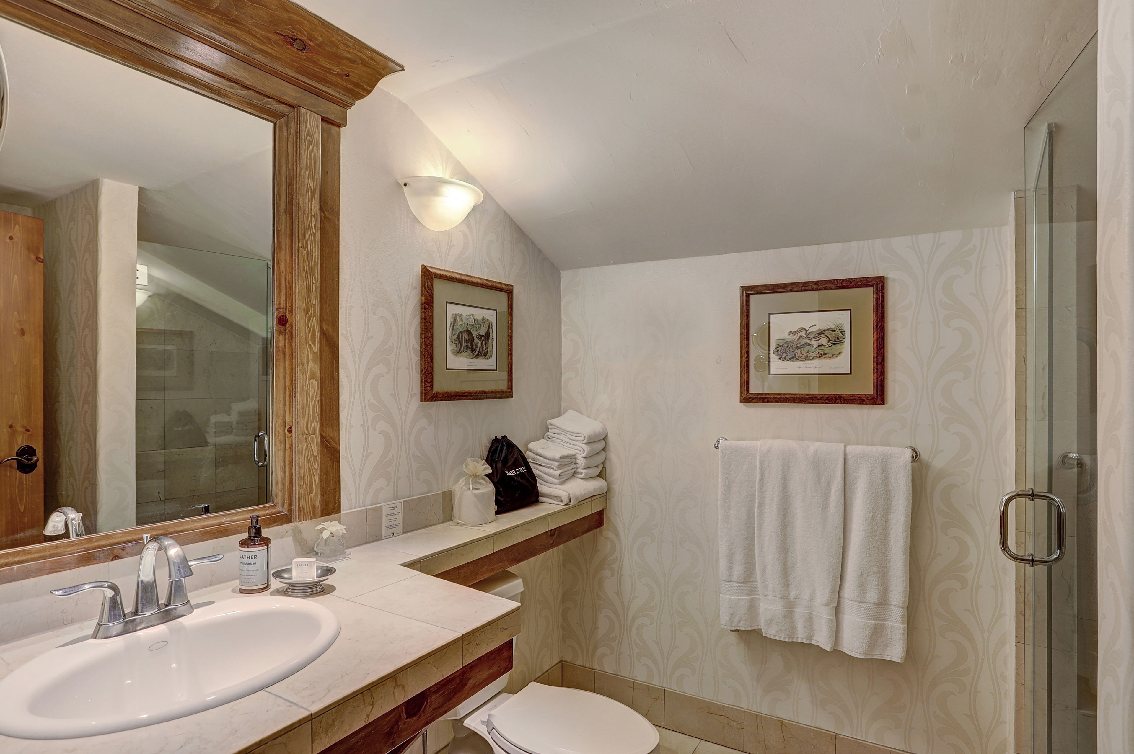 A bathroom with a large mirror, a sink, a toilet, and a glass shower enclosure.