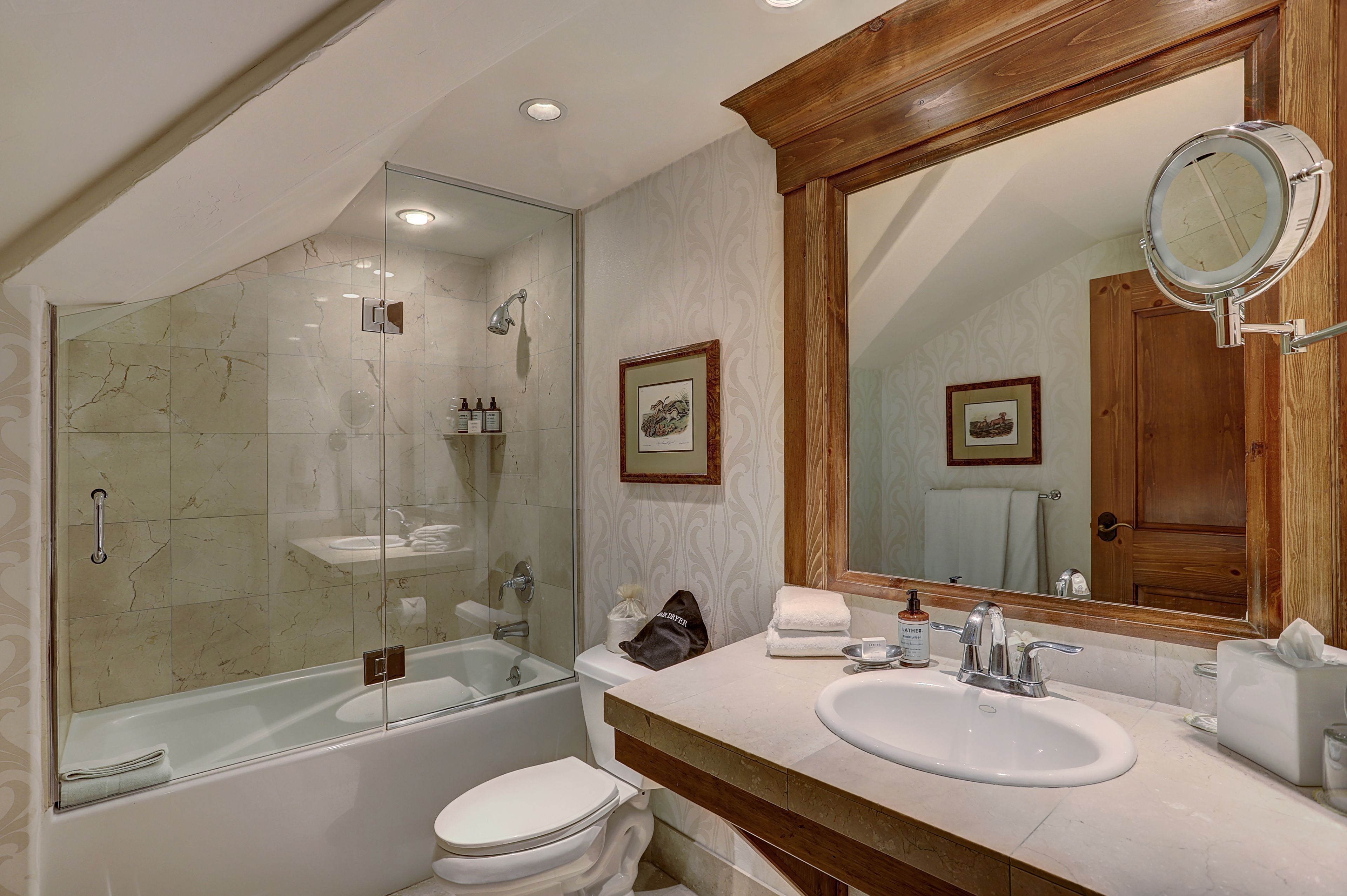 A modern bathroom with a glass-enclosed shower, a bathtub, a sink, and a large mirror.