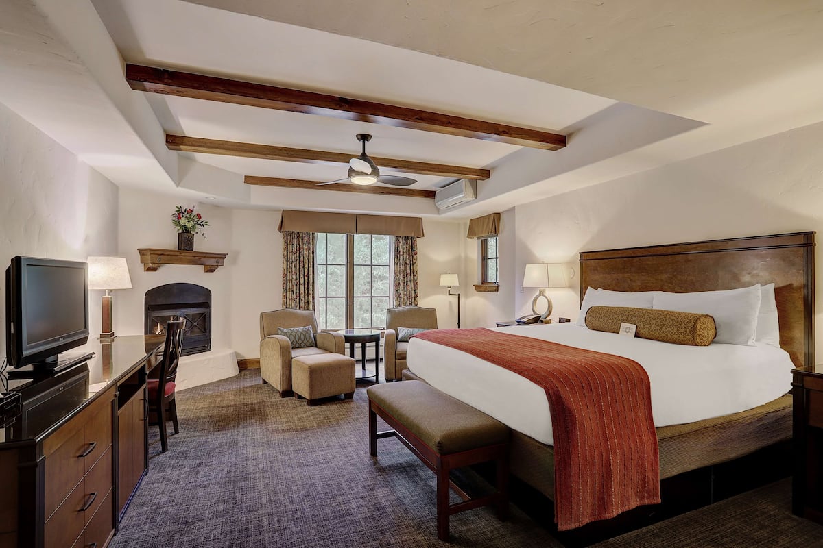 A hotel room with a bed, a TV, a fireplace, a desk, and a chair.