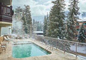 Una piscina al aire libre, sombrillas, sillones reclinables de piscina