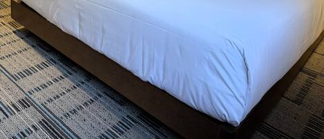 A hotel room with two beds, a nightstand with a lamp, and a patterned carpet.