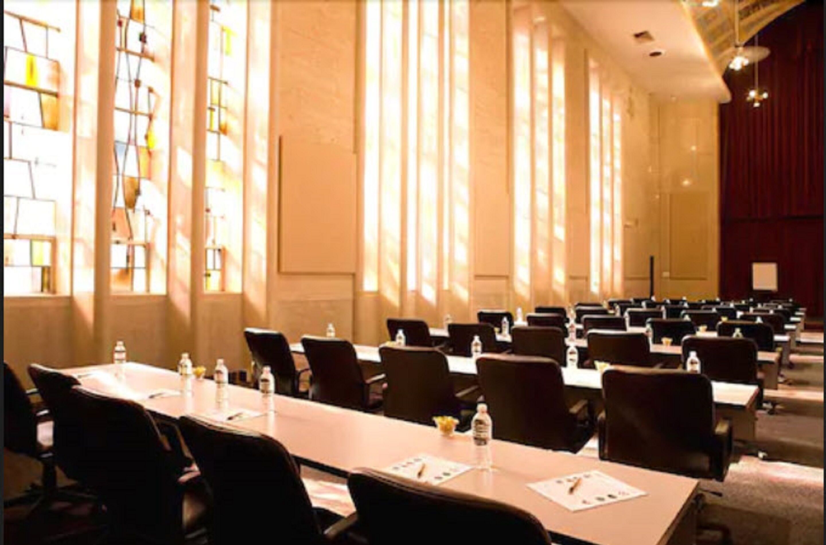 Une salle de conférence avec de longues tables, des chaises et des bouteilles d’eau.