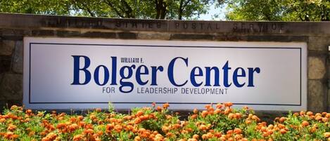 A sign for the Bolger Center for Leadership Development with a backdrop of trees and marigold flowers.