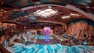 A spacious lobby with a central fountain, multiple staircases, and a large rock wall.