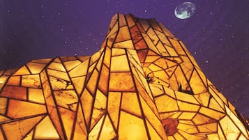 A building with a geometric, angular design and a large, illuminated structure resembling a pyramid.
