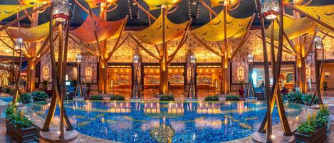 A spacious indoor pool area with a central water feature, surrounded by modern architectural elements and ambient lighting.