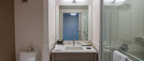 A modern bathroom with a toilet, sink, and glass shower enclosure.