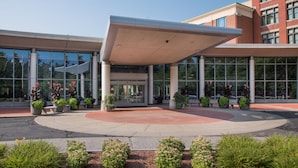 A modern building with a covered entrance, large windows, and potted plants.