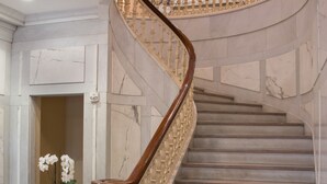 A marble staircase with a wooden handrail and a decorative balustrade.