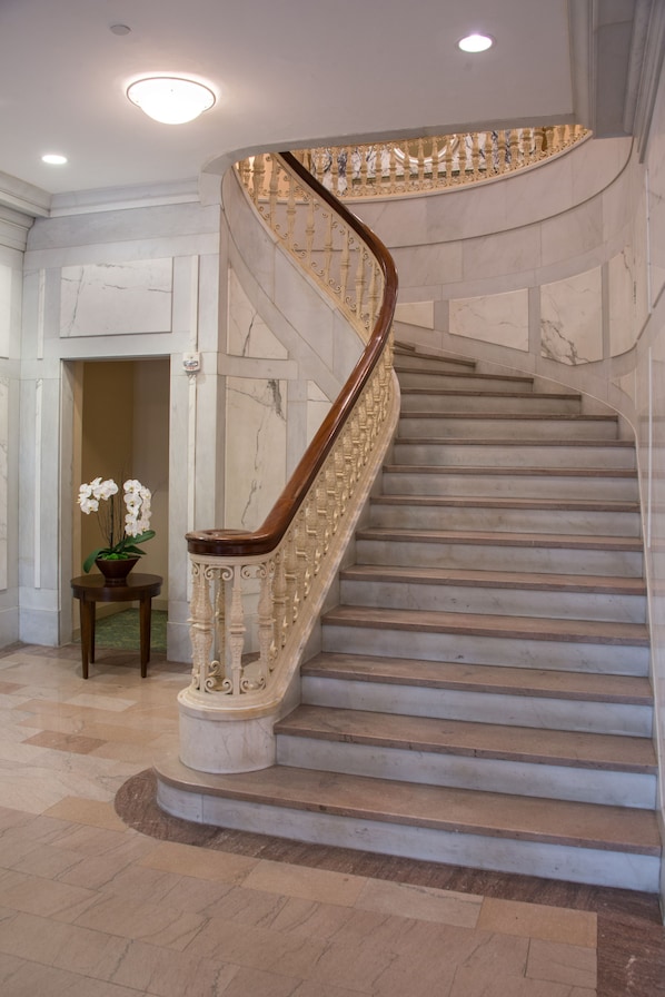 A marble staircase with a wooden handrail and a decorative balustrade.