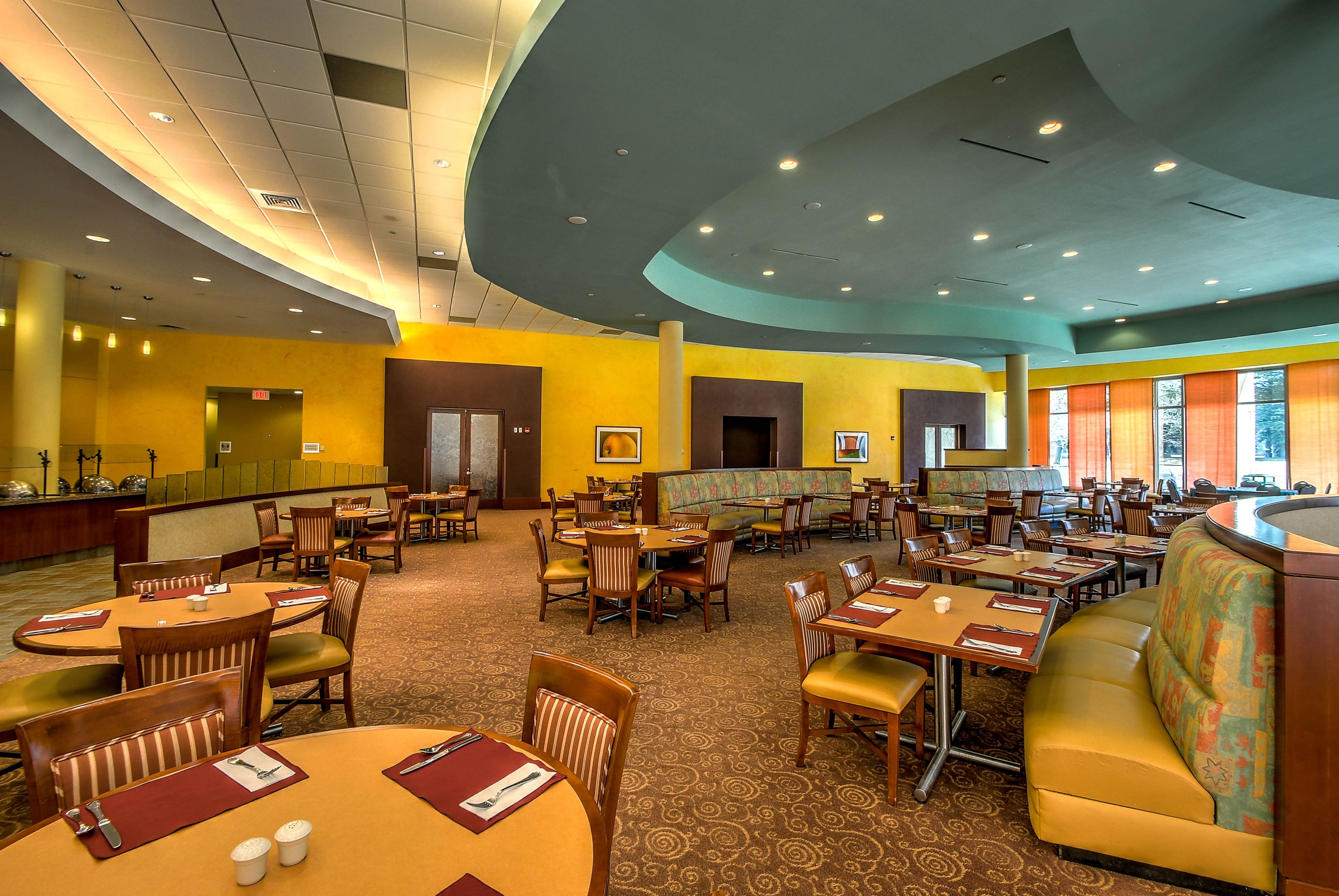 A spacious restaurant with multiple seating areas, including booths and tables, and a variety of chairs.