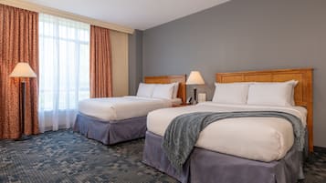Una habitación de hotel con dos camas, un ventanal con cortinas y suelo alfombrado.