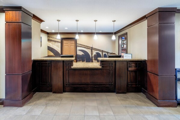 A kitchen with dark wood cabinetry, a central island, pendant lighting, and a mural of a bridge on the wall. - Staybridge Suites Colorado Springs North by IHG (Colorado Springs)