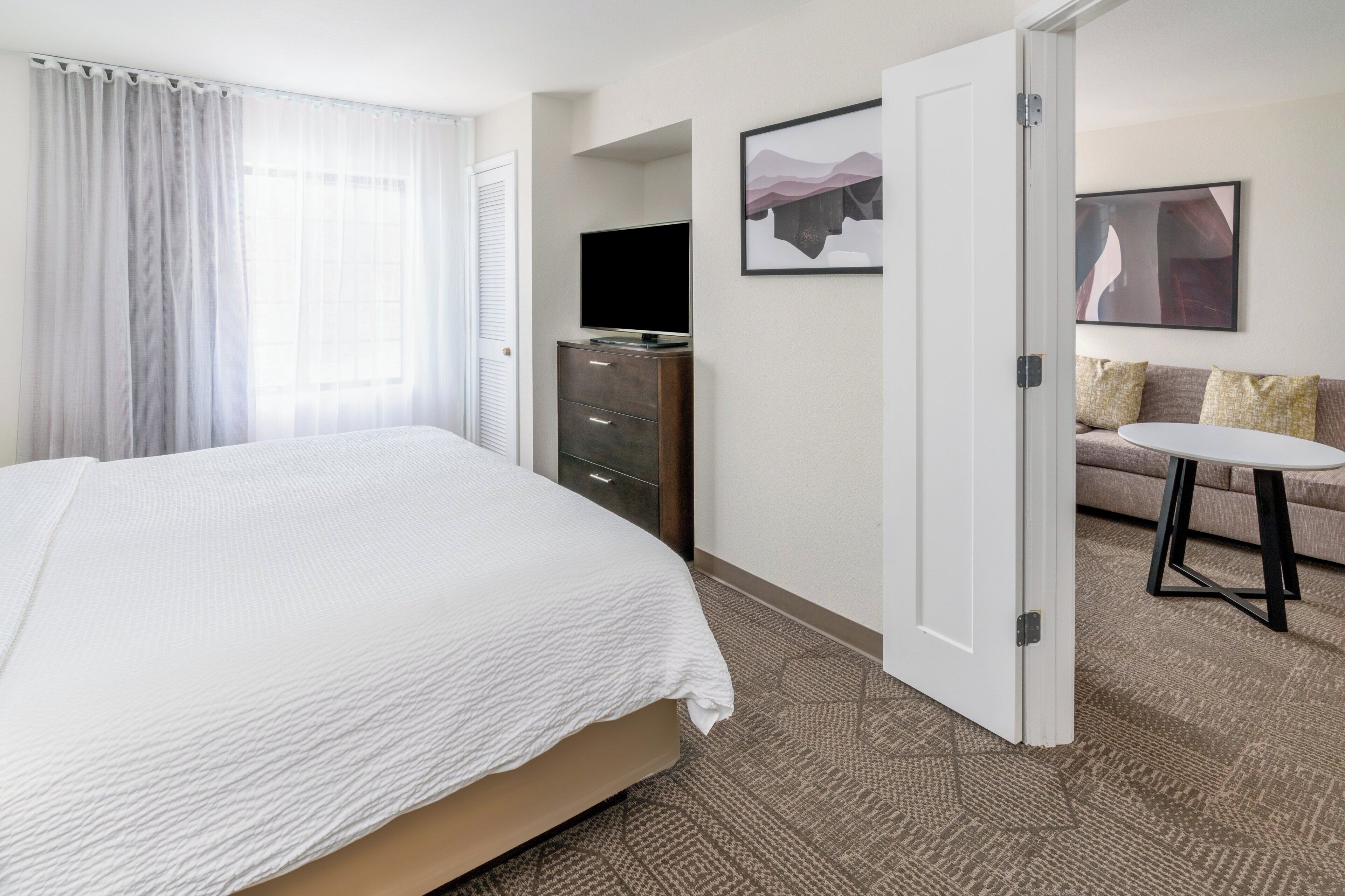 Een hotelkamer met een bed, een televisie, een bank en een kleine tafel.