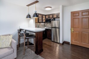 Una cocina moderna con una isla central, armarios de madera oscura, electrodomésticos de acero inoxidable e iluminación colgante.