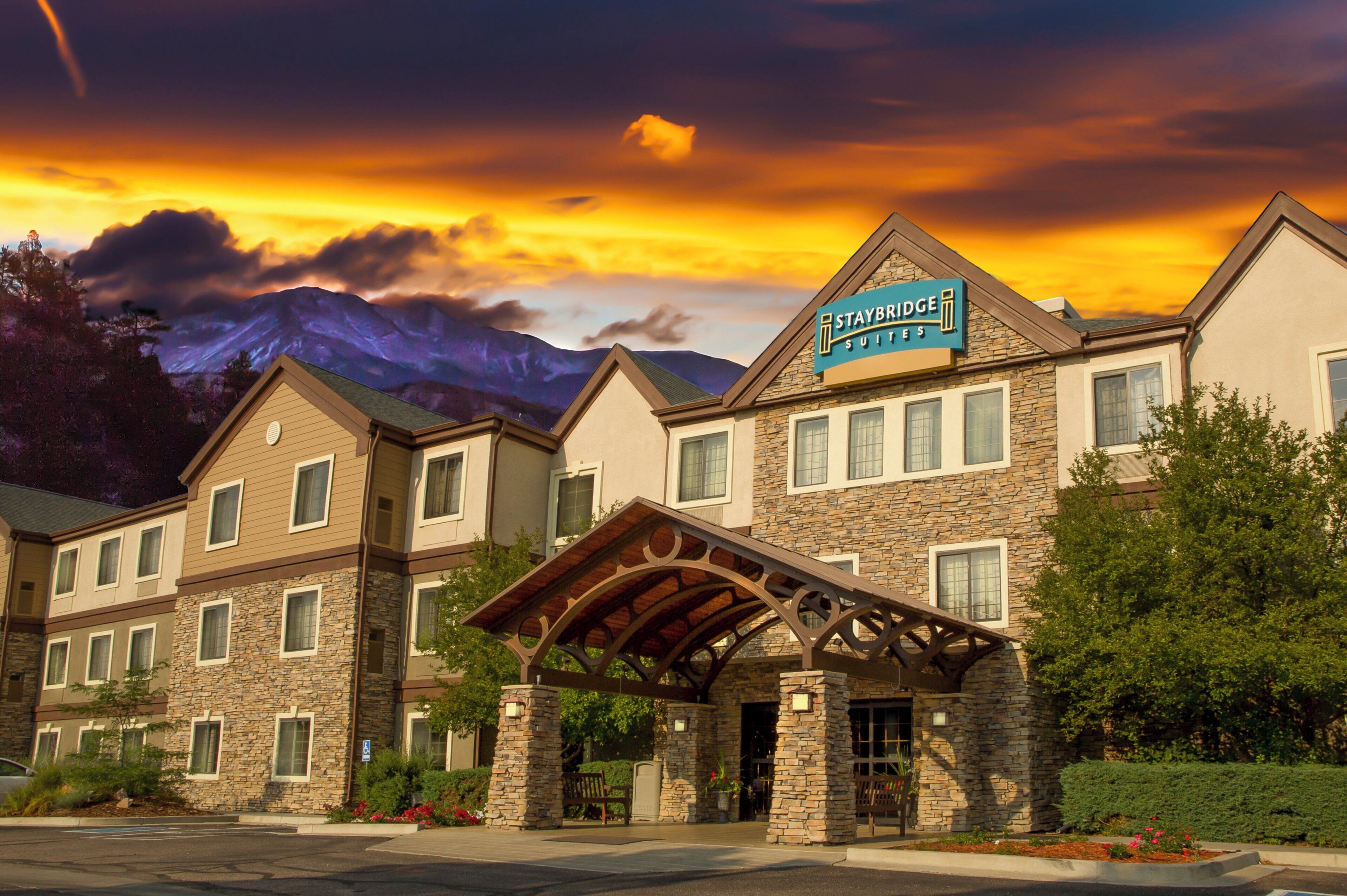 Un hotel Staybridge Suites con fachada de piedra, varias ventanas y un acceso cubierto.
