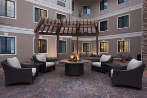 Un patio con un brasero, muebles de mimbre y una pérgola.