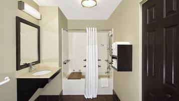 A bathroom with a sink, mirror, shower, and towel rack.