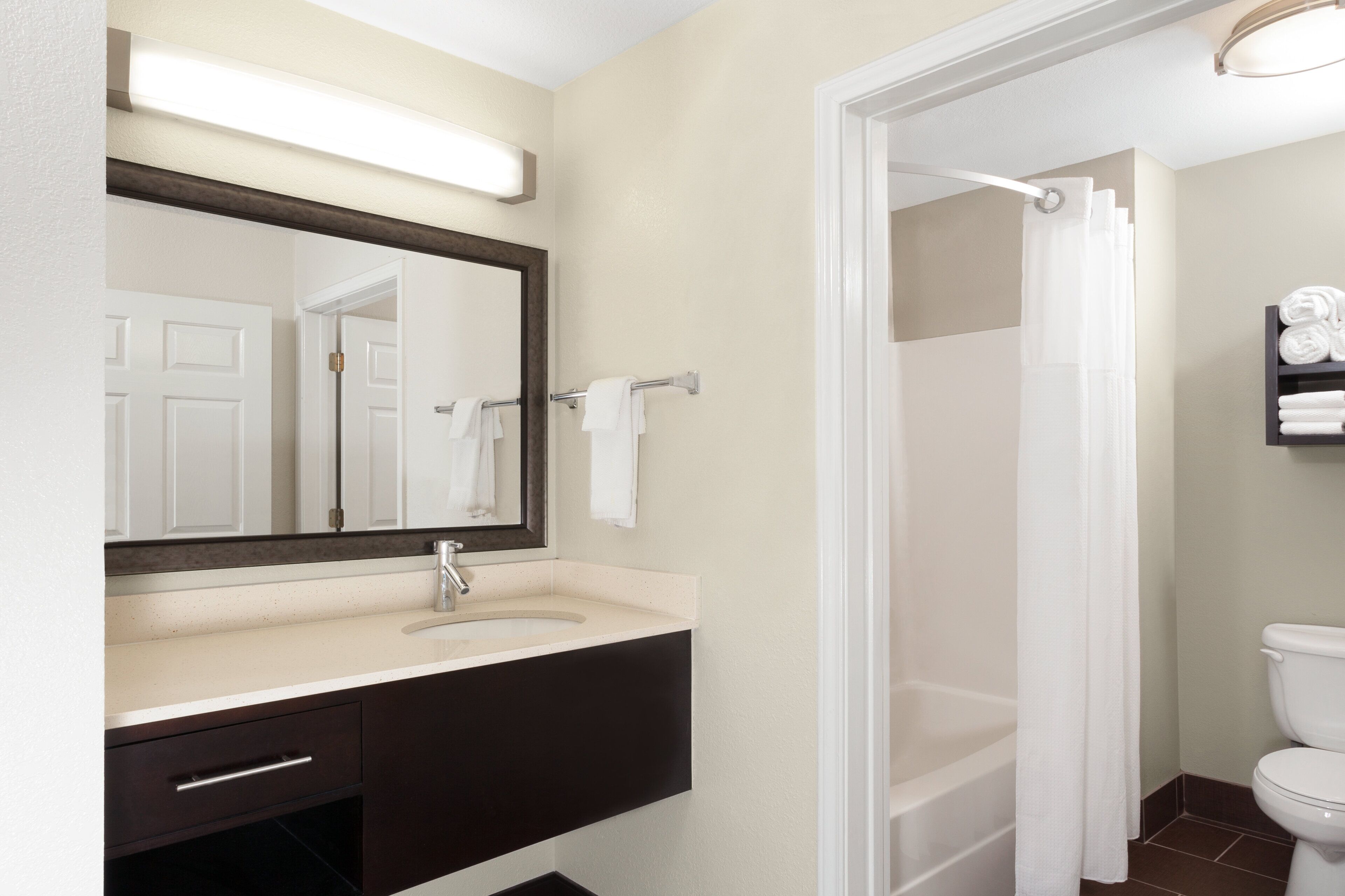 A bathroom with a sink, mirror, towel rack, and a shower curtain.