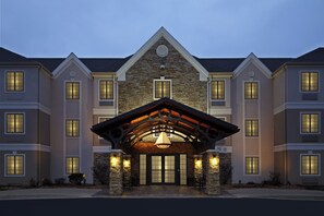 A multi-story hotel with a stone facade, large windows, and a prominent entrance with a wooden archway.