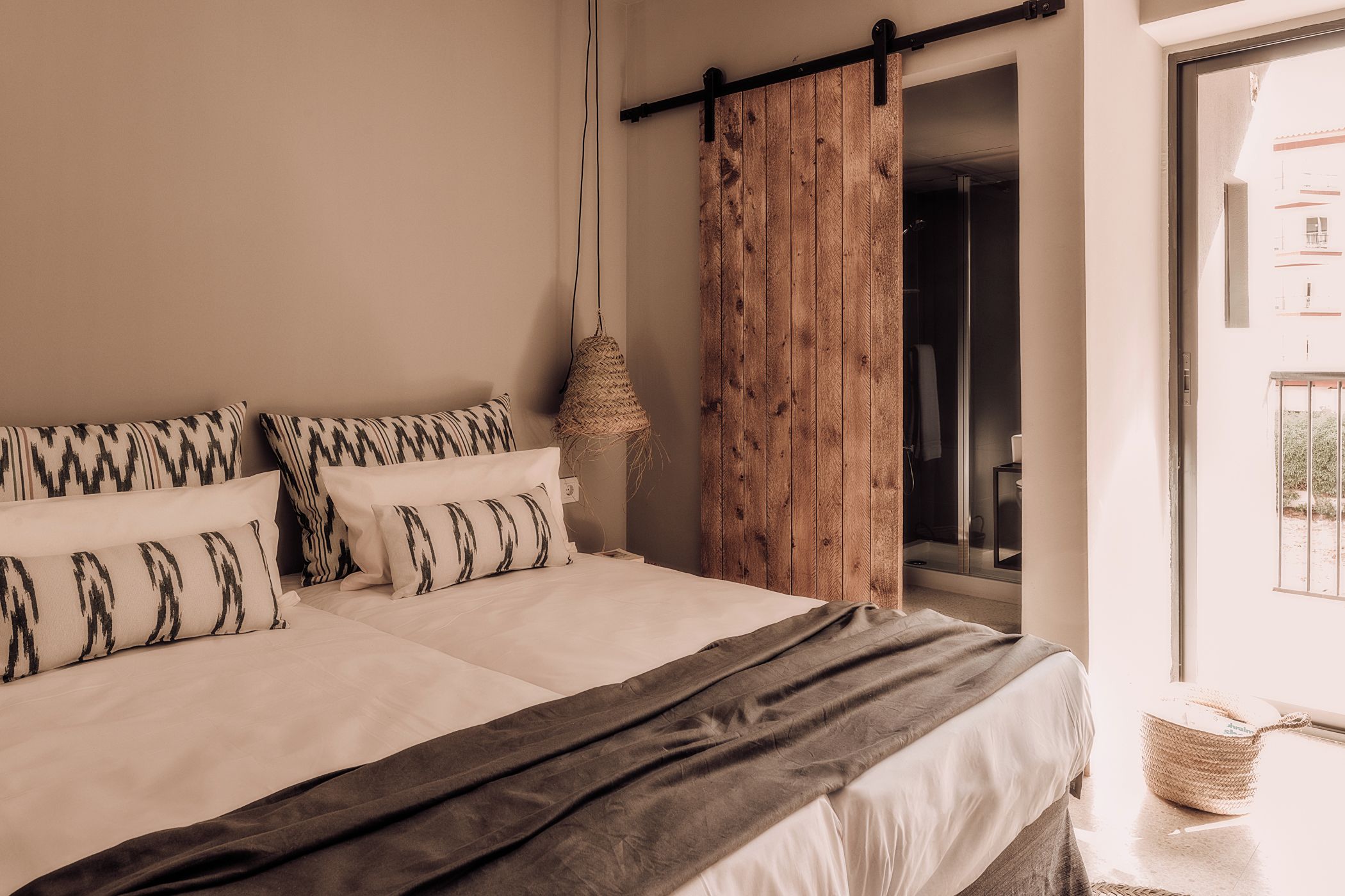 Ein Schlafzimmer mit einem großen Bett, einer Holztür und einer Pendelleuchte.