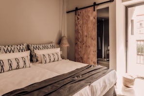 A bedroom with a large bed, a wooden door, and a hanging light fixture. - Caramelo Palma Beach +18 (Palma de Mallorca)
