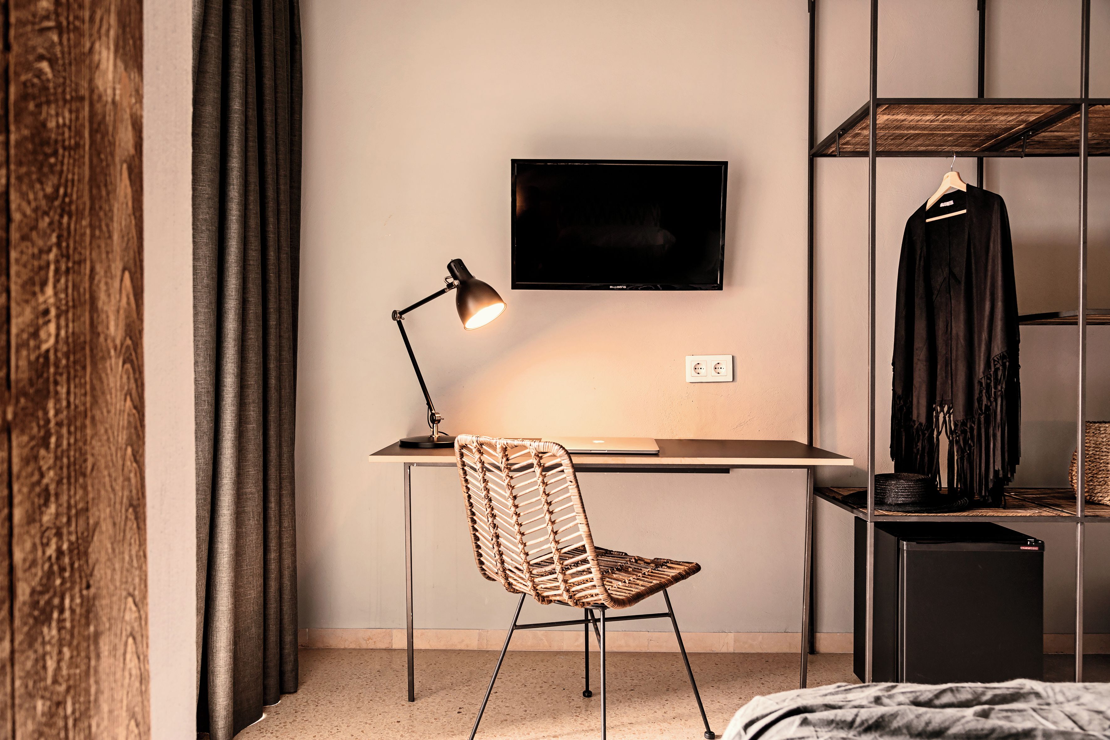 Een moderne hotelkamer met een bureau, een stoel, een televisie en een bed.