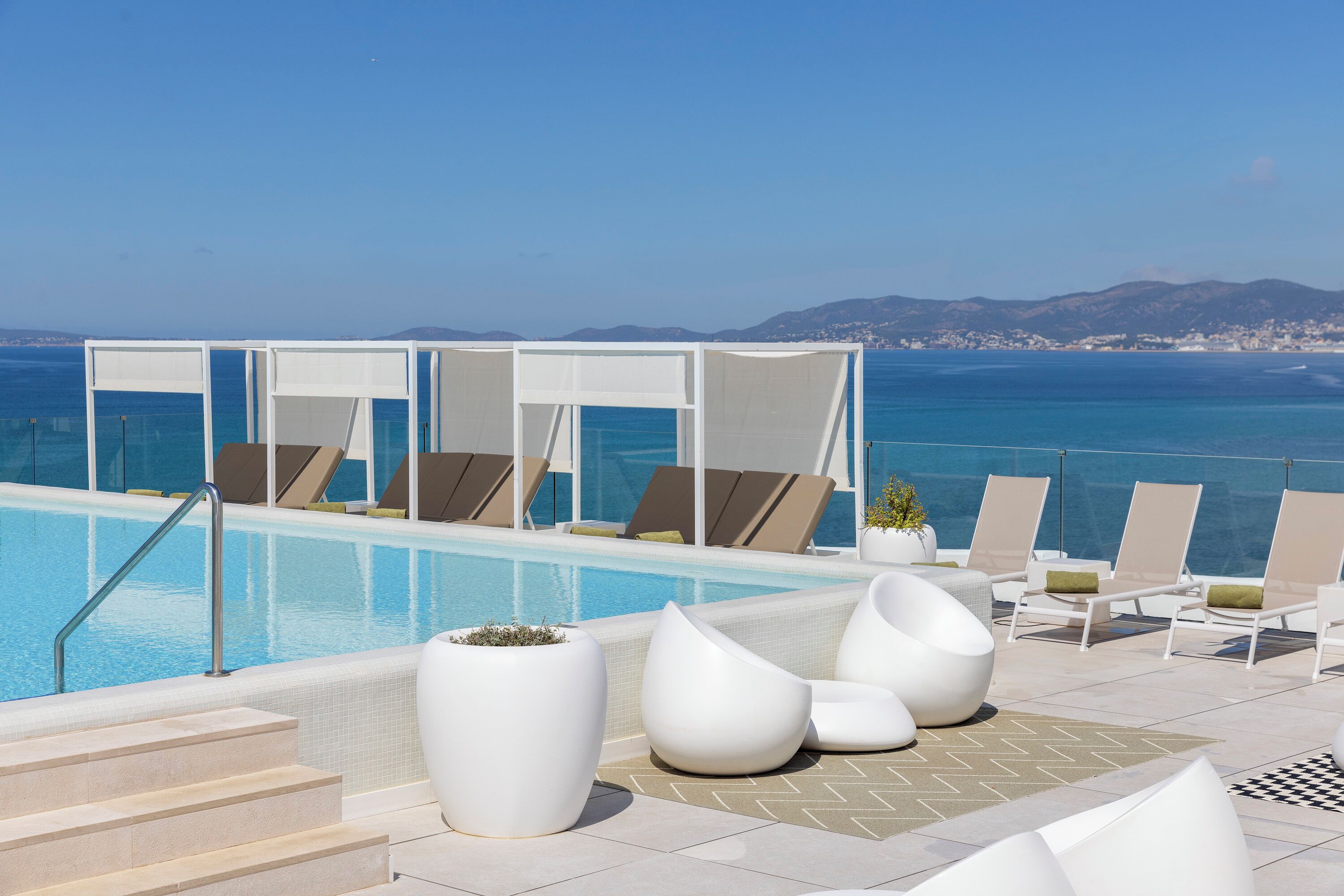 Zona junto a la piscina con sillones de descanso y vistas al mar.