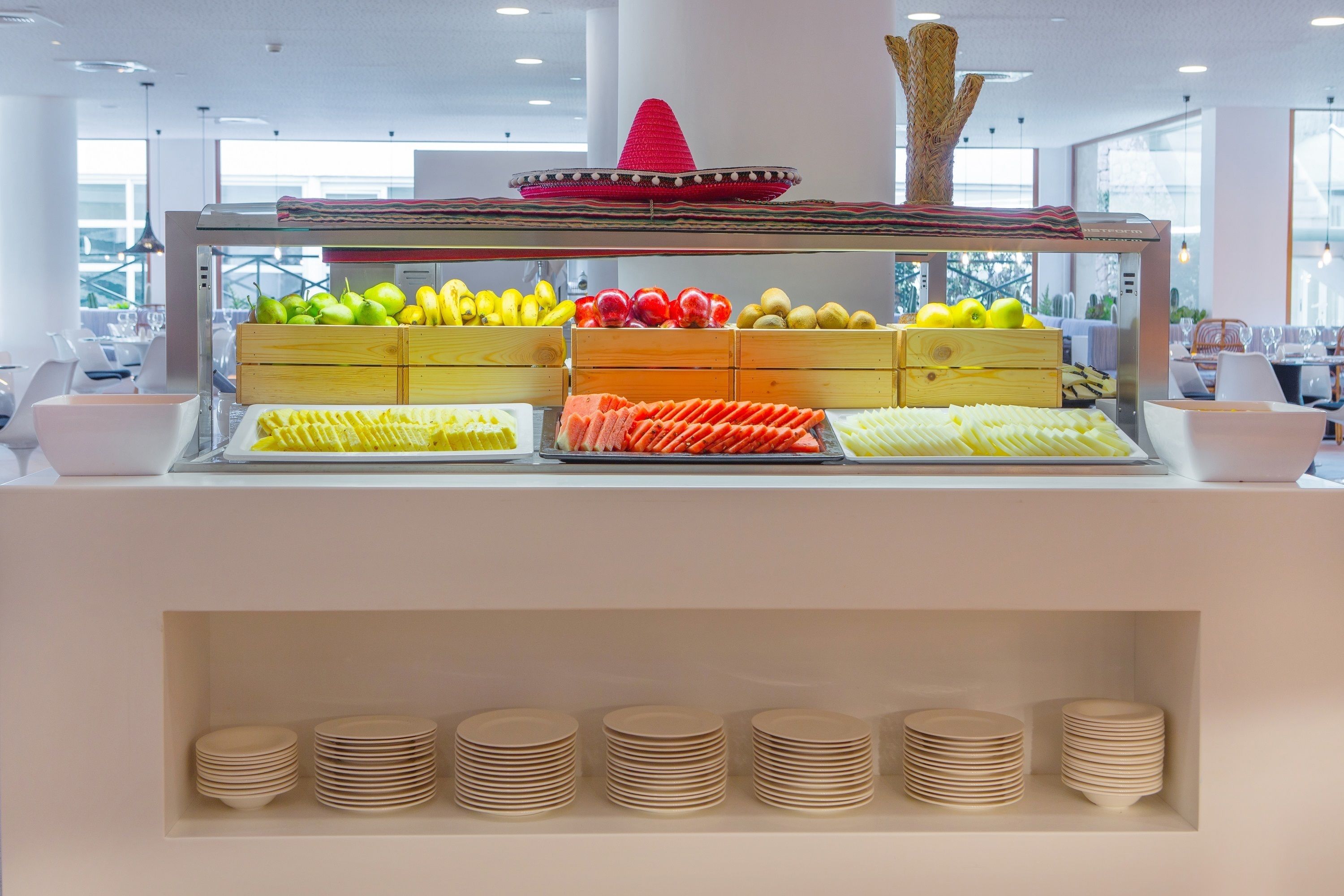 Zona de bufé con frutas y verduras dispuestas en cajas de madera.