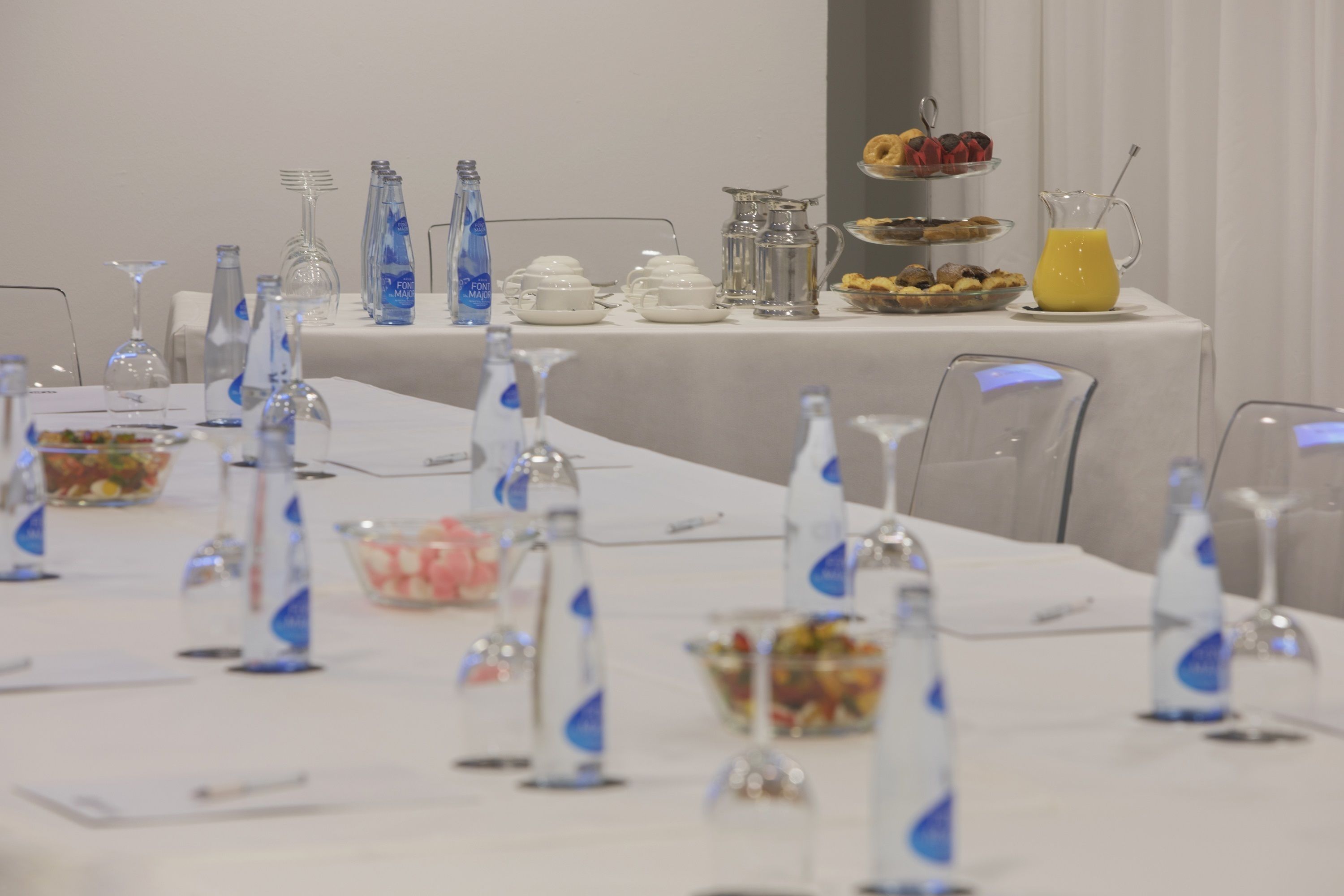 Una mesa con una variedad de alimentos, vasos y botellas de agua dispuesta para un bufé de desayuno.