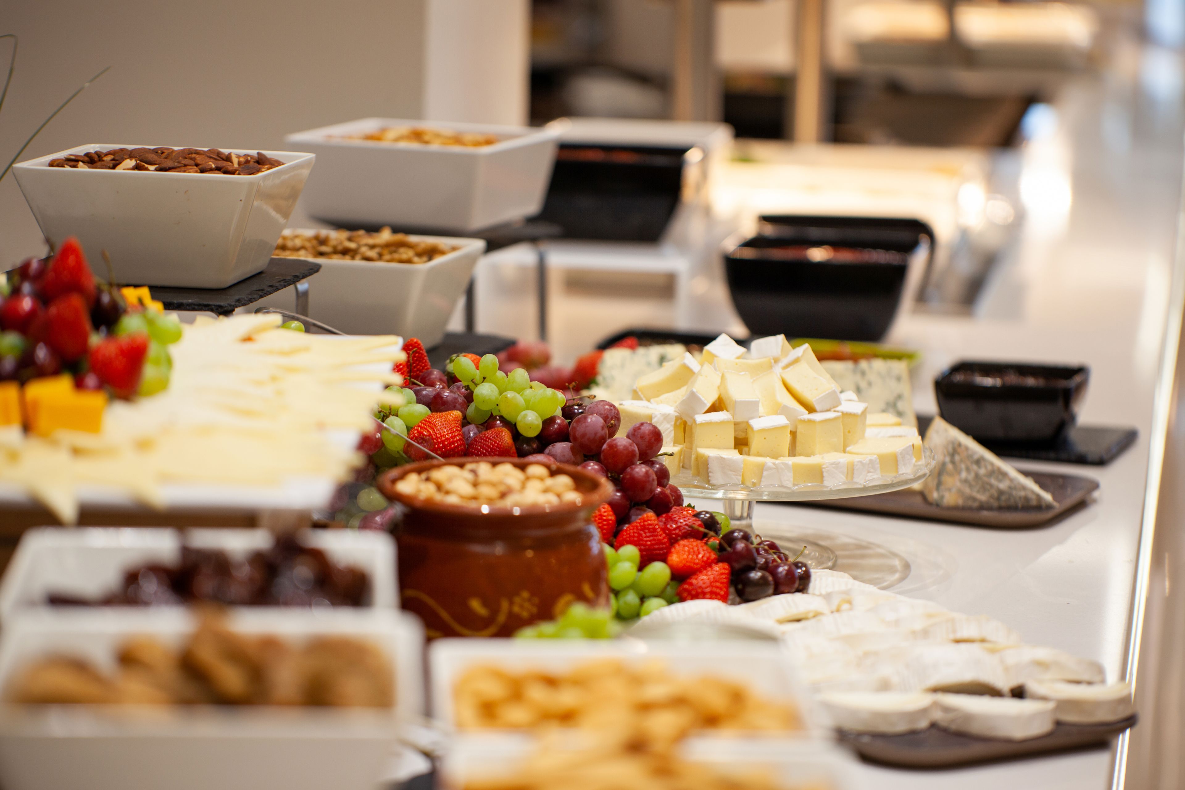 A buffet with various cheeses, fruits, and nuts.