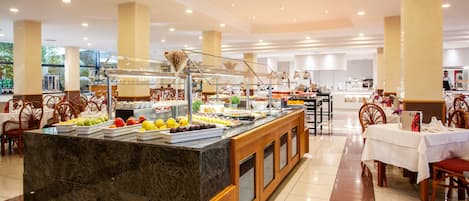 A buffet area with a marble counter, various food items, and wooden chairs.