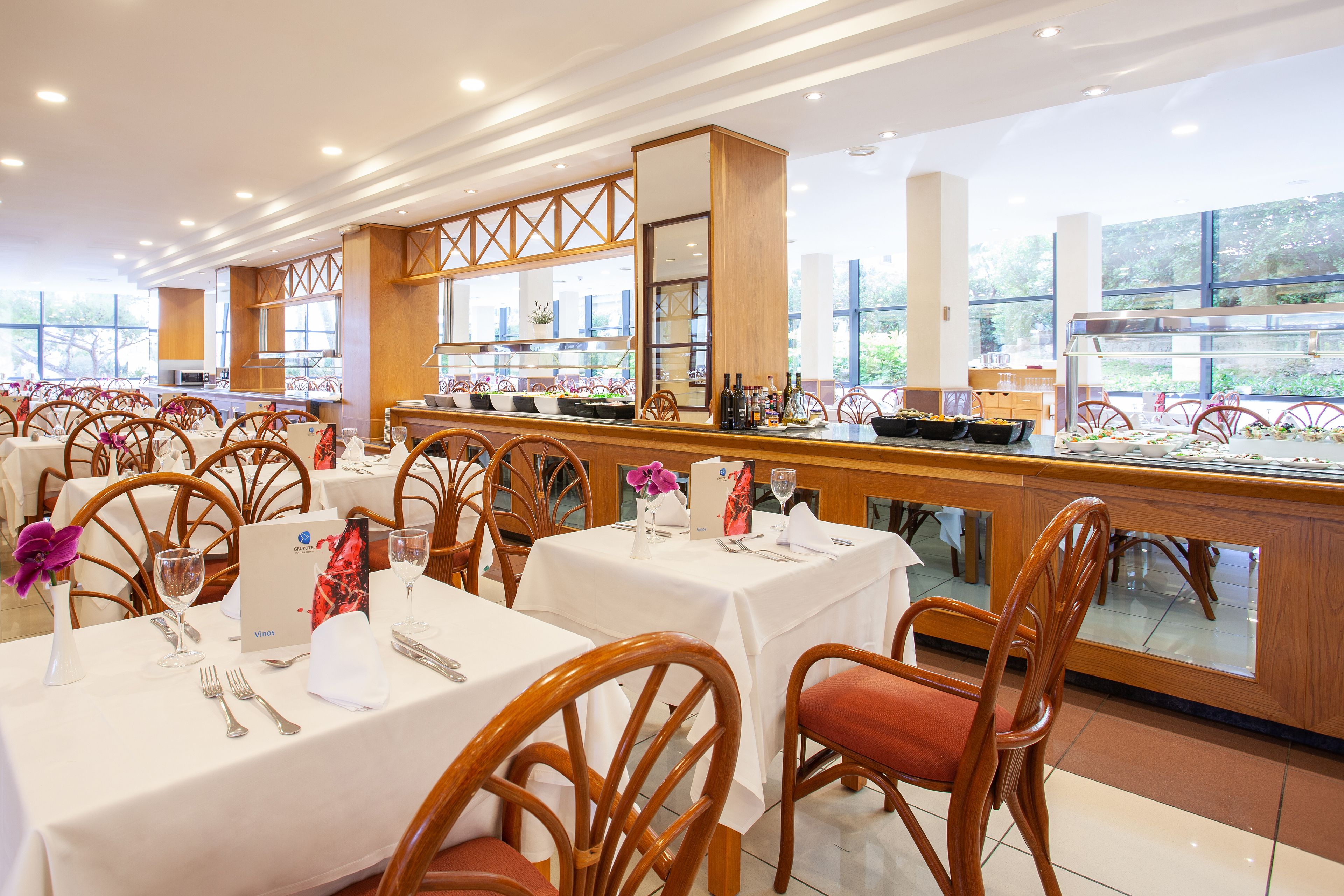 Un restaurant doté de nombreuses tables, de chaises en bois et d’un espace buffet.