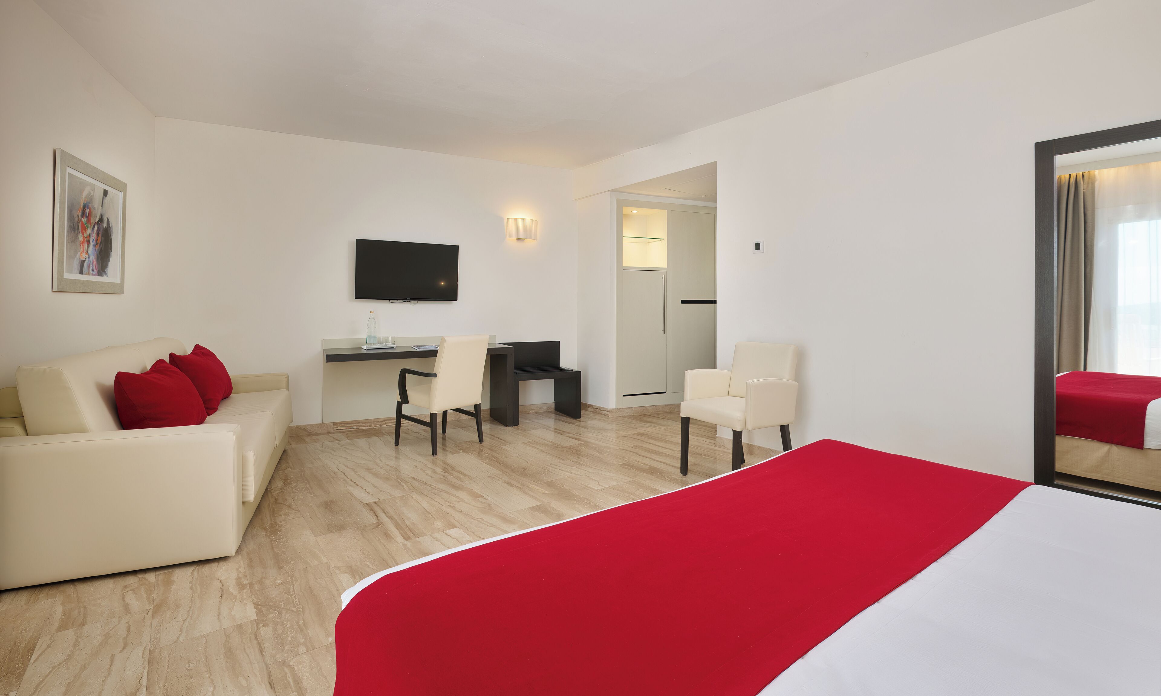 Una habitación de hotel con una cama, un escritorio, una silla y un sofá.
