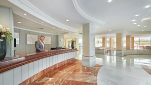 A spacious lobby with a marble reception desk, large pillars, and a view of the outdoors. - Grupotel Taurus Park (Palma de Mallorca)