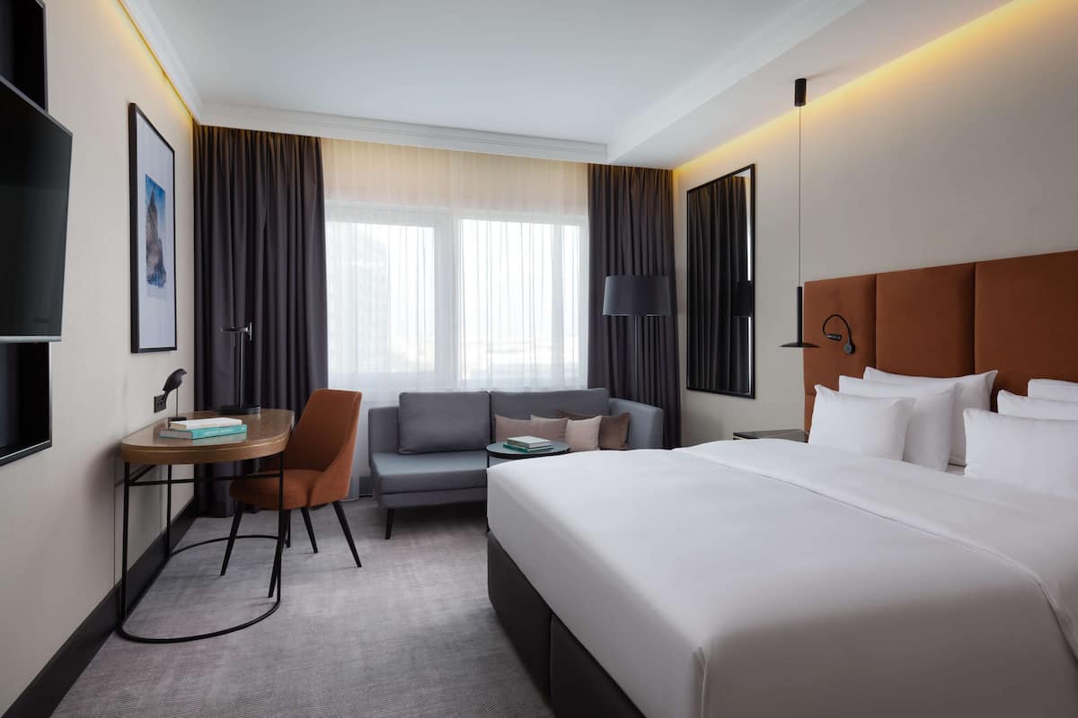 Una habitación de hotel con cama, sofá, escritorio y silla.