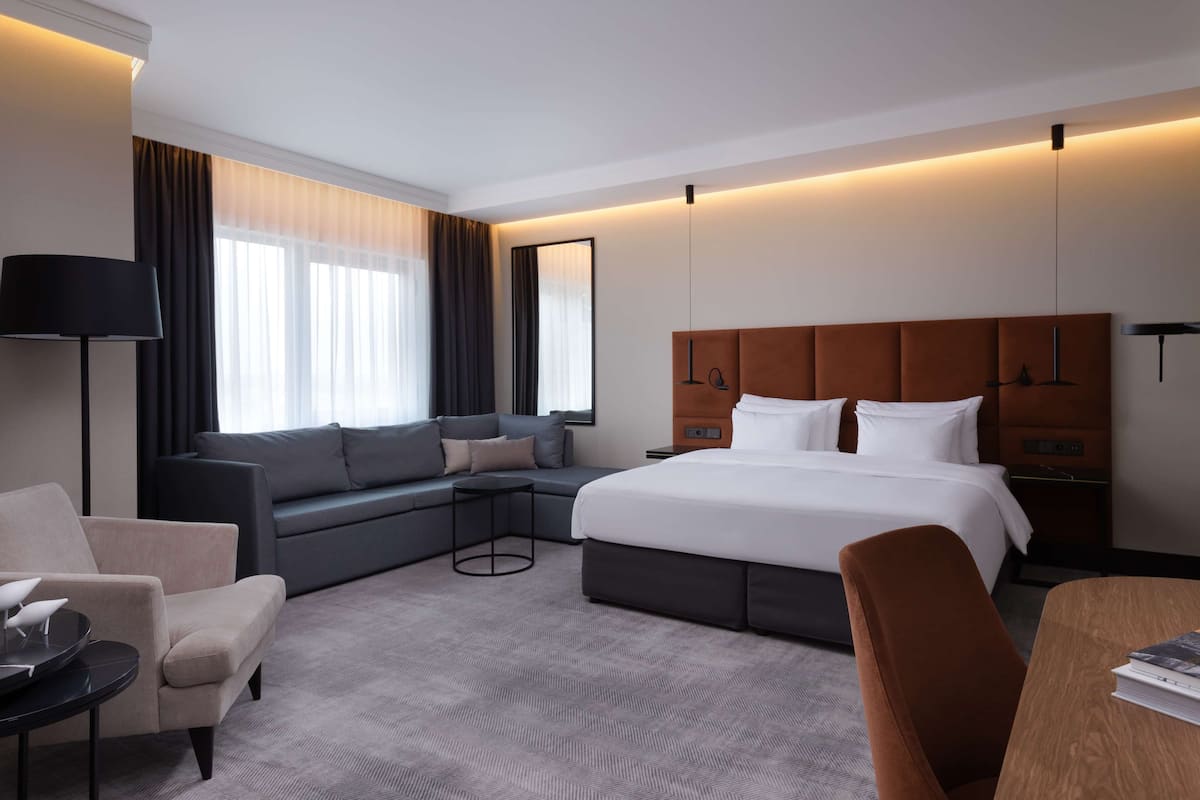 Una habitación de hotel moderna con una cama grande, un sofá, un escritorio y una silla.
