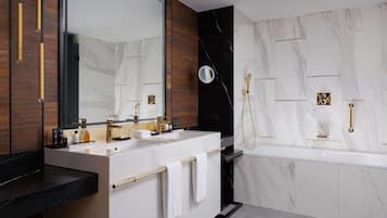 Ein modernes Badezimmer mit einem Doppelwaschtisch, einem großen Spiegel, einer Handbrause und einer Badewanne mit Marmorwand.